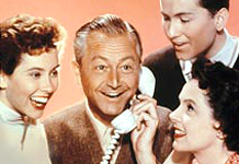 Jim Anderson receives an exciting phone call while his wife and older children look on.